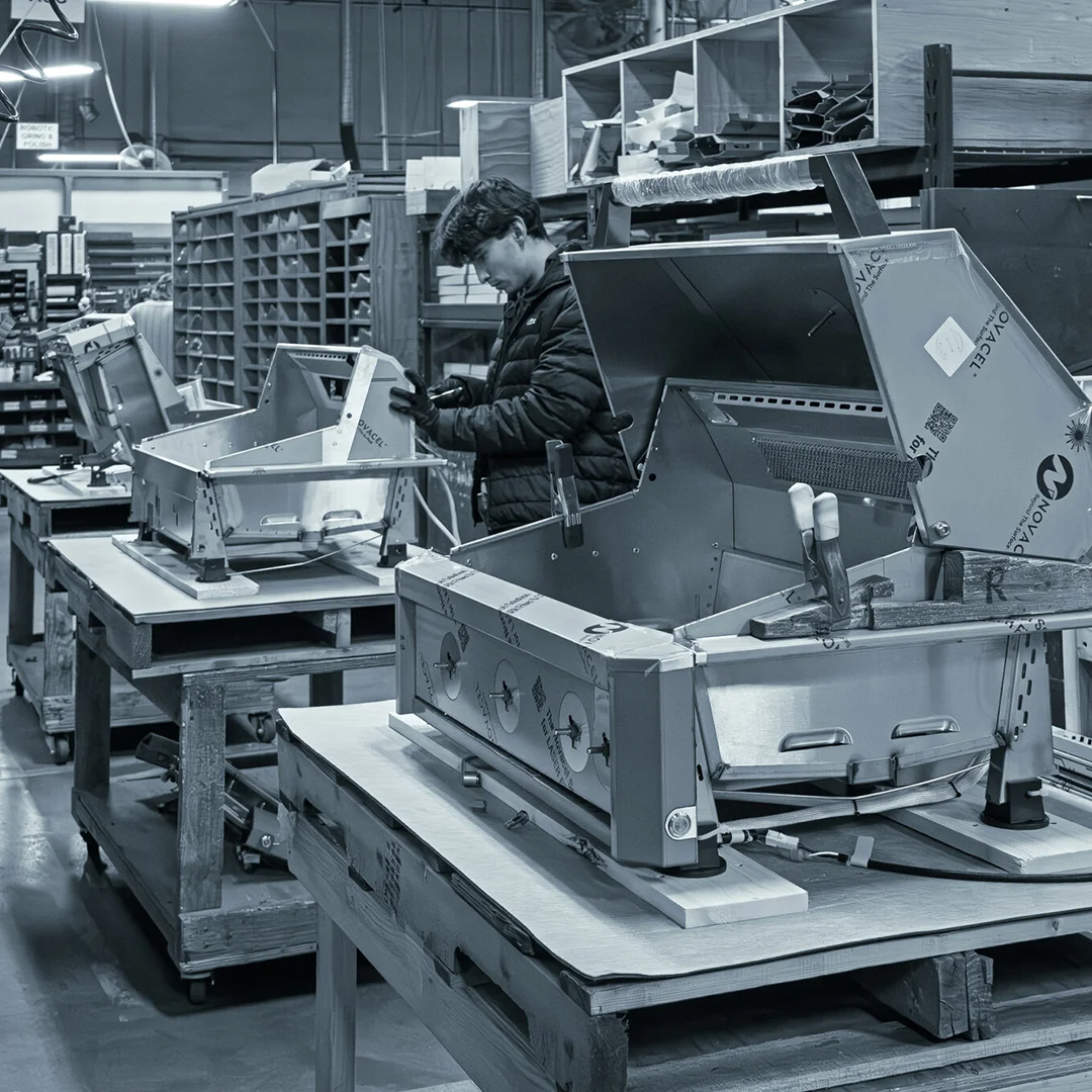 Worker assembling stainless steel American Outdoor Grill units on a factory production line